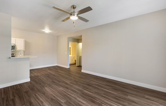 Experience cozy comfort in our living room, complete with a gentle ceiling fan overhead and a glimpse of our stylish kitchen in the background at Boulders at Lookout Mountain Apartment Homes, Phoenix,