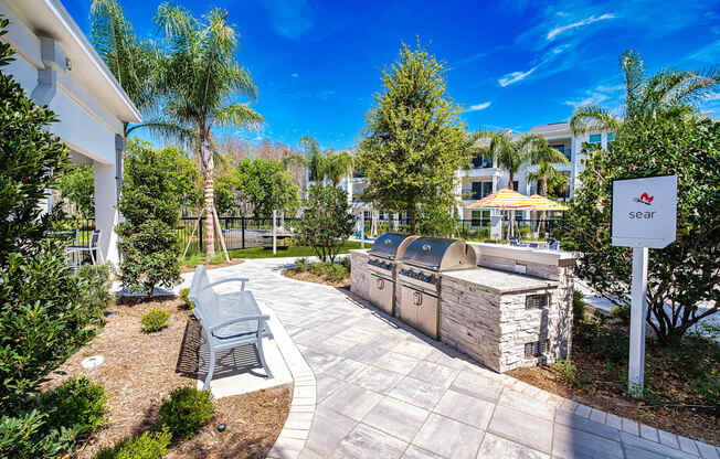 a stone patio with a grill and benches next to a building at Altis Grand Suncoast, Land O' Lakes, 34638