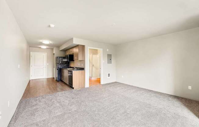 A spacious living room with a kitchenette in the background.