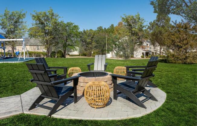 a fire pit with chairs around it in the middle of a lawn