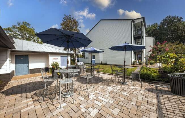 a patio with tables and chairs and umbrellas in front of a house