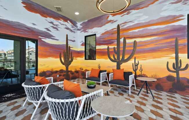 A room with a desert mural on the wall and a table with chairs in front of it.