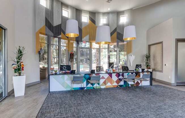 A modern office space with a colorful reception desk and a view of the outside through the glass doors.