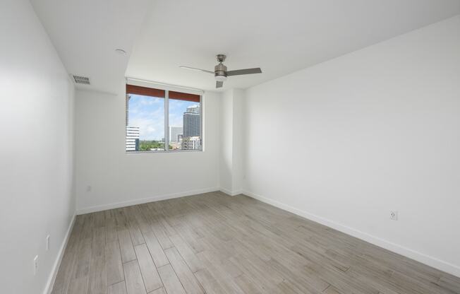 a bedroom with hardwood floors and a large window