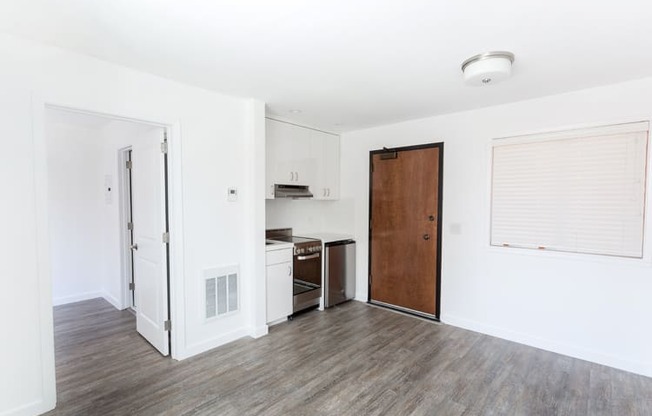 an empty living room with a kitchen in the background