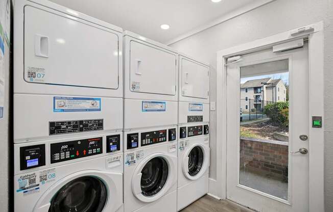 A row of washing machines are lined up in a laundry room.
