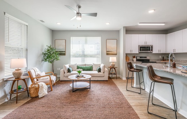 a living room with a couch and a table in front of a kitchen