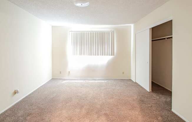 an empty room with a closet and a window