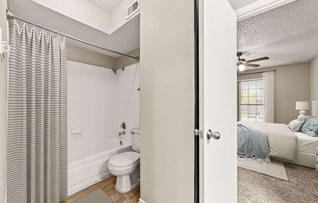 an open bathroom with a bed and a toilet in a bedroom