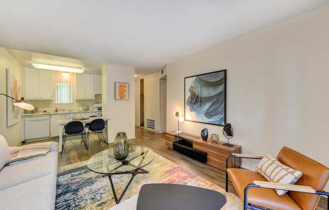 Living Room with View of Dining Area, Hardwood Inspired Floor, Colorful Rug, Brown Chair and White Sofa at Renaissance Park Apartments, Davis, CA