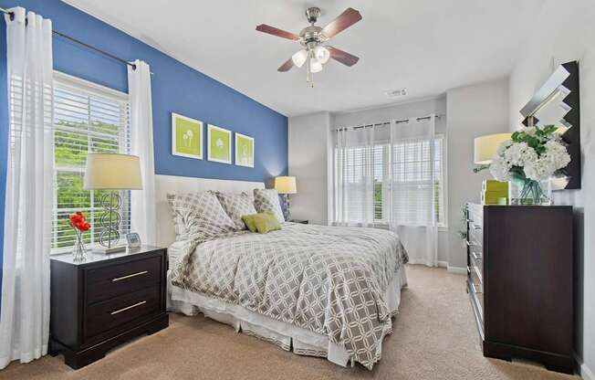 A bedroom with a bed, nightstand, and a ceiling fan.