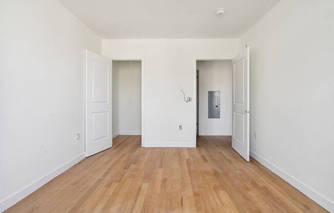 a living room with white walls and wooden floors and white doors