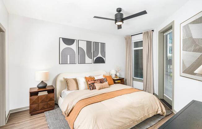 Spacious bedroom showcases wood-style flooring, modern ceiling fan, and large windows for abundant natural light.