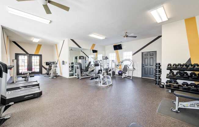 A spacious gym with a variety of equipment including treadmills, weights, and exercise machines.