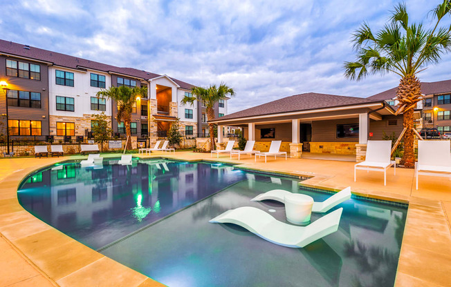 Swimming pool with chairs and a building in the background at The Parker Austin, Pflugerville, 78660
