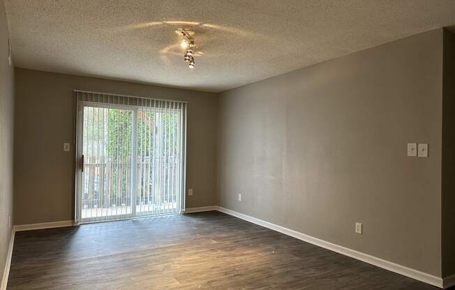 an empty living room with wood floors and a sliding glass door