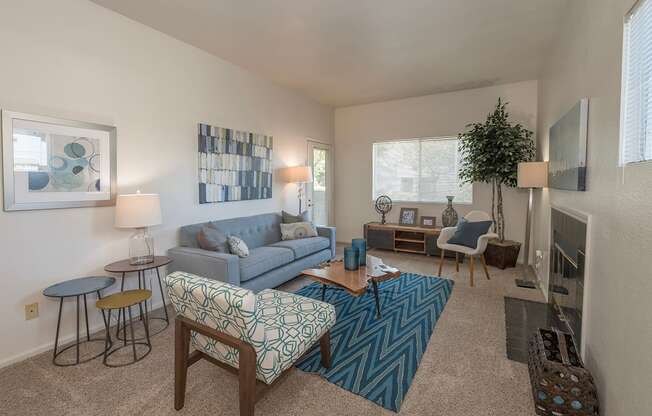 A living room with a blue couch and a patterned chair at Autumn Oaks Apartments, Roseville, CA, 95678