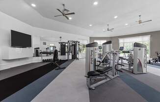 A spacious gym with a variety of equipment and a flat screen TV mounted on the wall.
