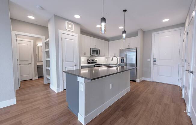 A modern kitchen with a large island and pendant lights.