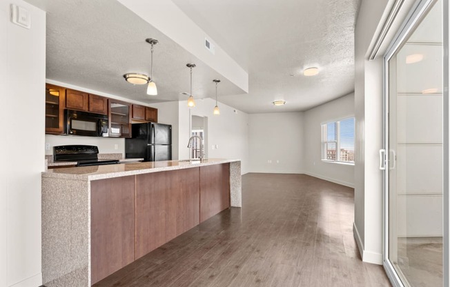 a kitchen and living room with hardwood floors and a sliding glass door