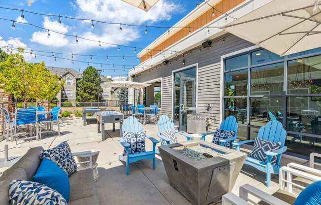 a patio with blue chairs and a fire pit