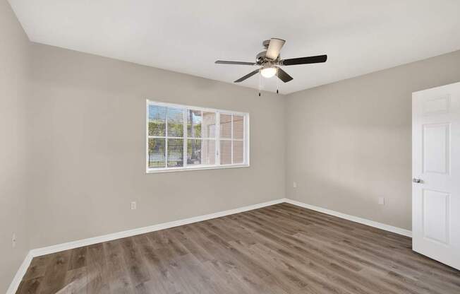 A room with a ceiling fan and a window with blinds.
