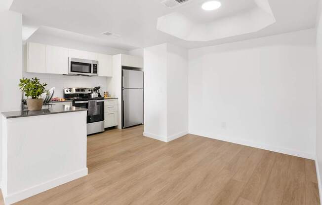 A kitchen with white cabinets and a wooden floor.