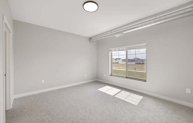 A room with a window and a carpeted floor.