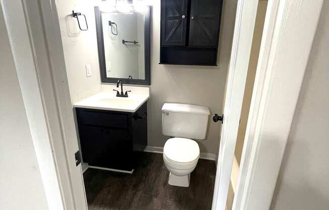 A bathroom with a toilet, sink and mirror.