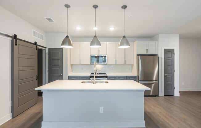 a white kitchen with a large island and stainless steel appliances