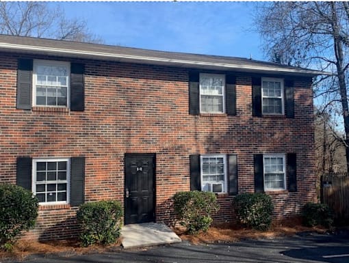 a brick house with black shutters and a black door