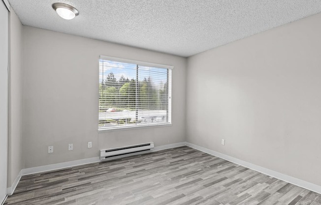 A room with a window and a wooden floor.