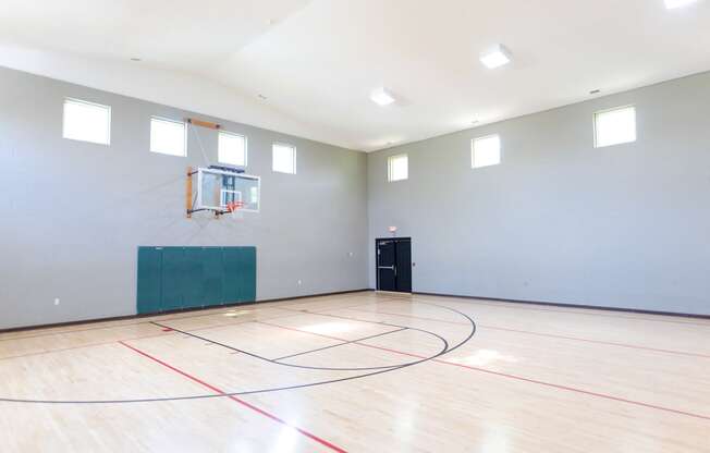 an empty gym with a basketball hoop and a door