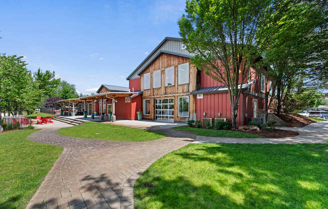 A building with a red and brown exterior is surrounded by a grassy area and a paved walkway.