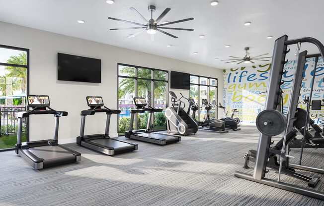 a gym with cardio equipment and windows in a building