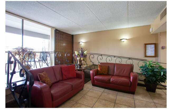 Two red couches in a room with a window.