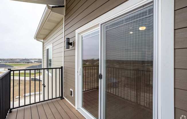 A sliding glass door with a screen on the balcony of a house.