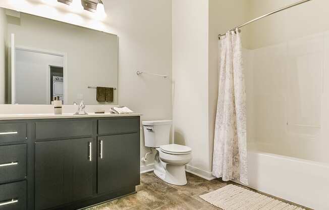 a bathroom with black cabinets and a white bathtub