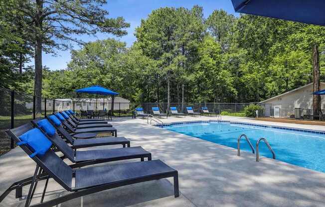 A pool area with sun loungers and a blue umbrella.
