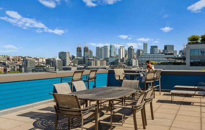 a woman sits at a table on a terrace with a view of the city in the at Dexter Lake Union, Seattle, 98109