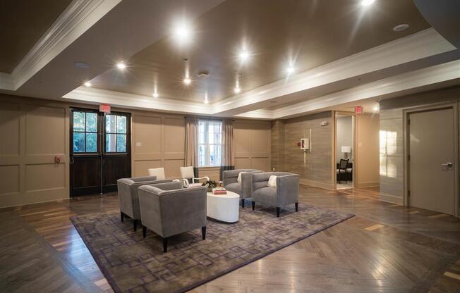 A spacious lounge with armchairs arranged around a central table under soft lighting.