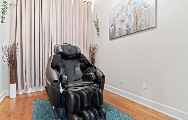 a massage chair sits in the corner of a room with a painting on the wall