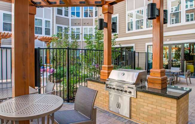 A patio with a grill and chairs.
