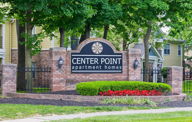 Leasing signage for Center Point Apartment Homes set against a brick entrance with vibrant landscaping and mature trees.