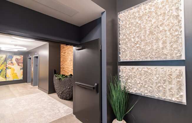 a hallway with a black door and a potted plant