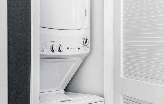 a white washer and dryer in a white closet at OLiVE DTLA in Los Angeles, CA