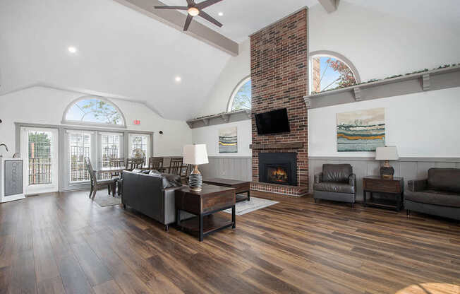 A community building with a fireplace, high ceiling and a ceiling fan at The Crossings Apartments in Grand Rapids, MI