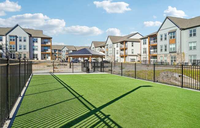 the yard is fenced in with a green lawn and a black fence