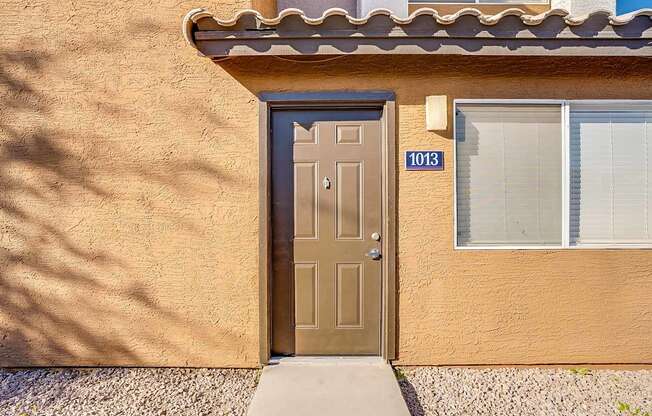 A brown door with the number 1013 on it is on a tan stucco house at Sterling Point Apartment Homes, Arizona, 85042
