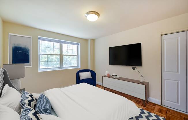 bedroom with bed, nightstands, large windows, parquet flooring, dresser and tv at shipley park apartments in washington dc